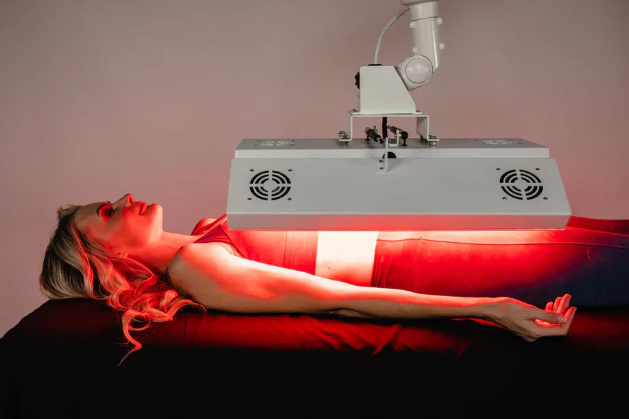 Woman receiving red light therapy on arms and upper body under ApolloARC canopy unit