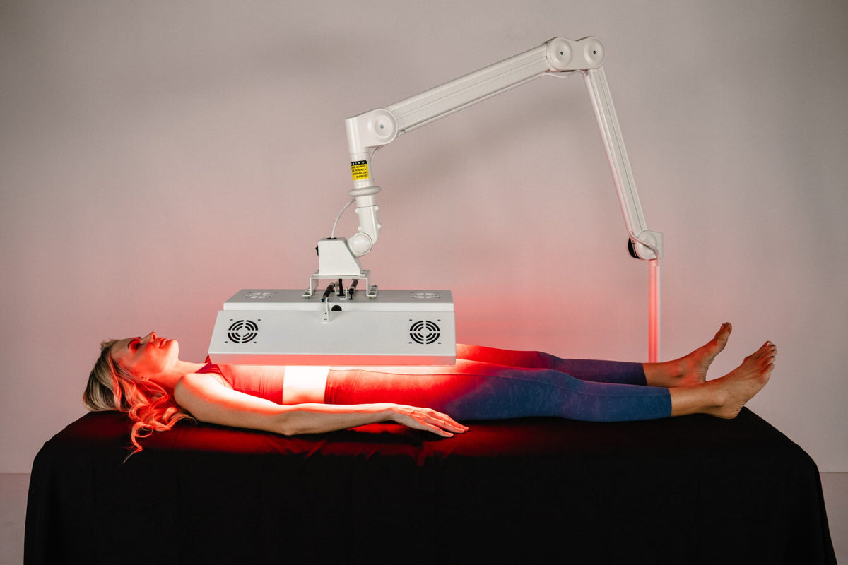 Woman receiving full-body red light therapy under the ApolloARC arc system on treatment table