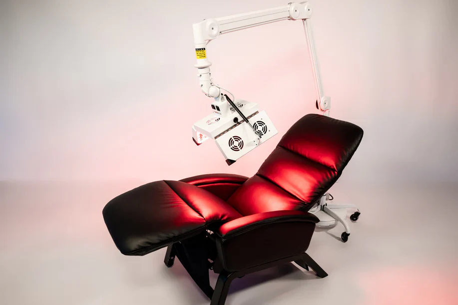ApolloARC red light therapy panel mounted over black recliner in studio setting