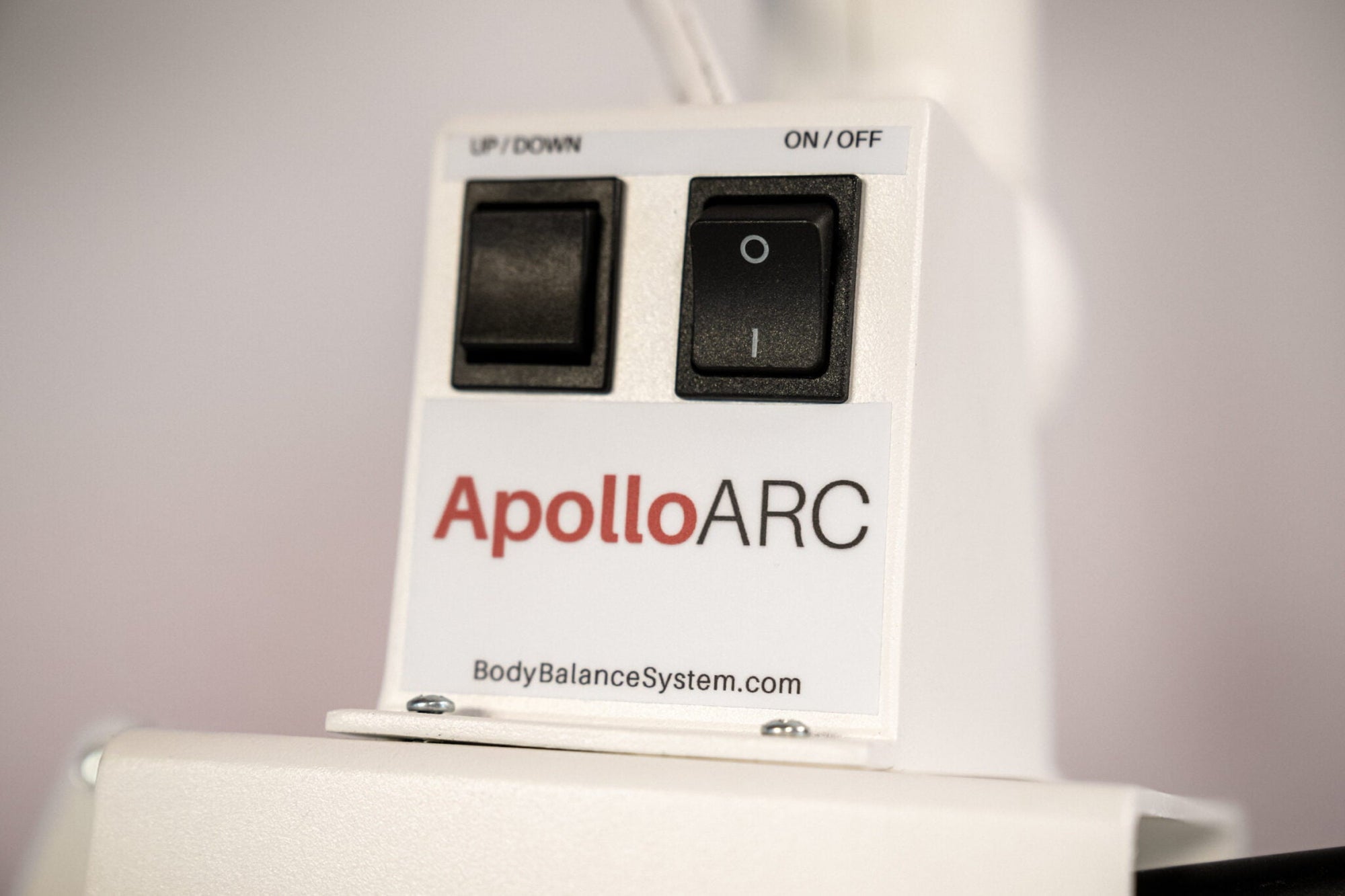 ApolloARC red light therapy panel glowing over red treatment bed with adjustable arm