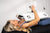 Woman lying on black treatment bed using ApolloARC red light therapy panel on face and chest