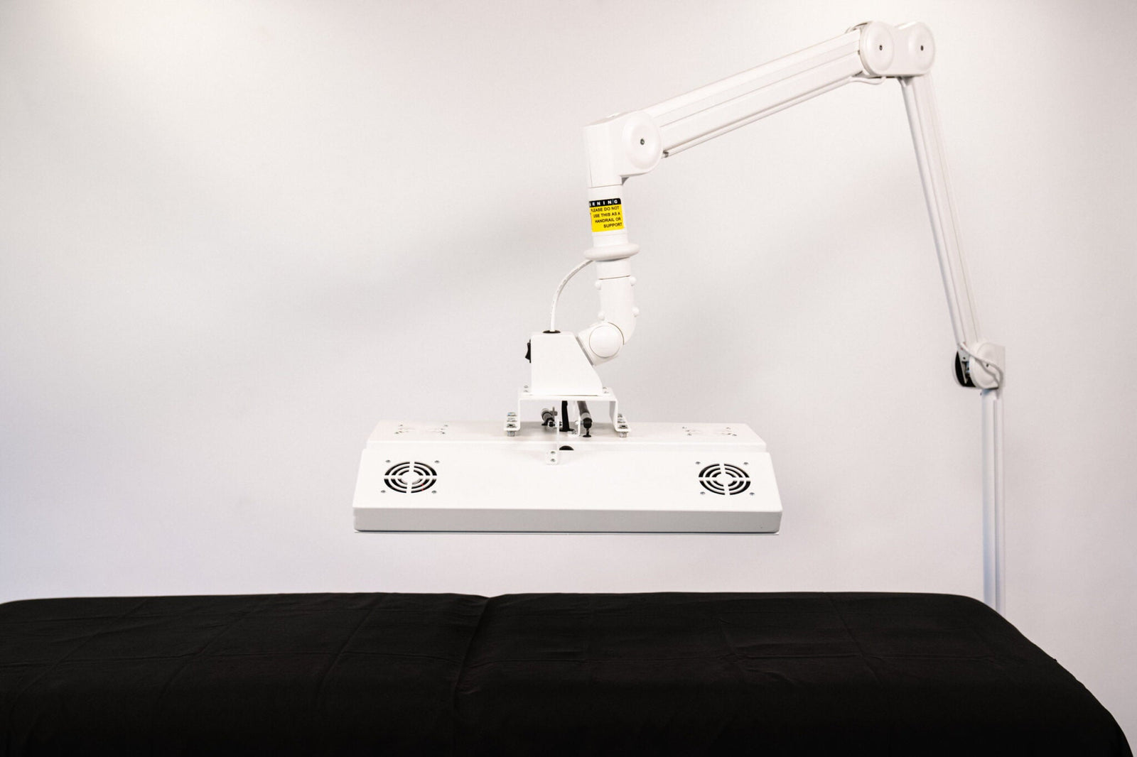 ApolloARC red light therapy system mounted on articulating arm above treatment table