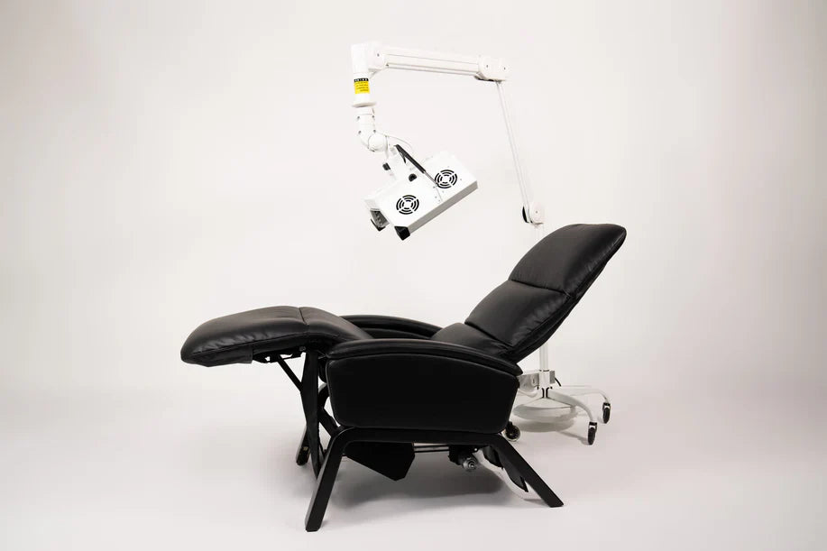 ApolloGLOW red light panel positioned over black recliner chair, side profile view