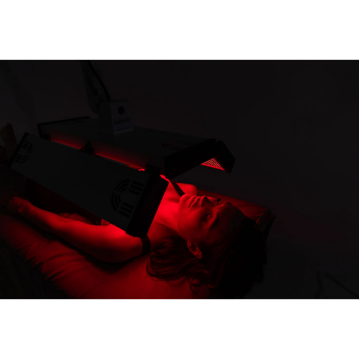 Body Balance System ApolloARC Red & Infrared Light Panel – woman lying in the dark under red light