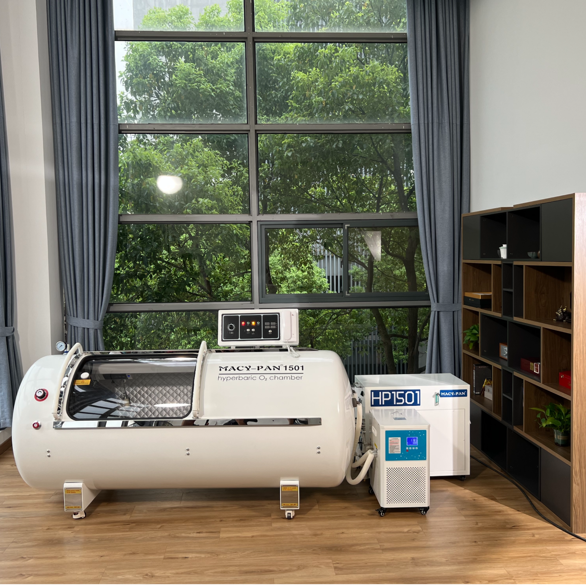Macy-Pan HP1501 Hard-Shell Lying Hyperbaric Chamber – white chamber next to the oxygen concentrator