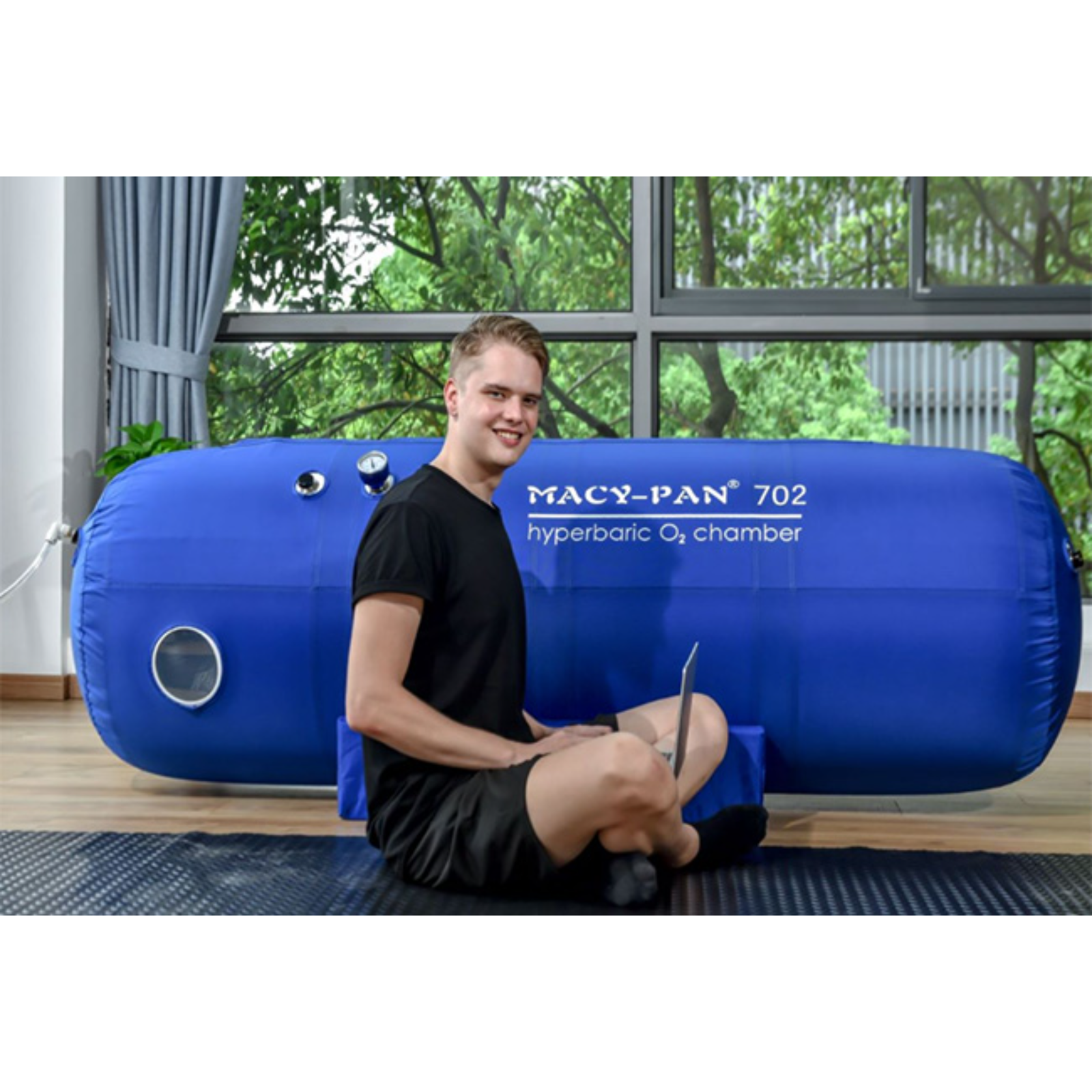 Macy-Pan ST702 Soft Lying Hyperbaric Chamber – man sitting with a laptop by the chamber