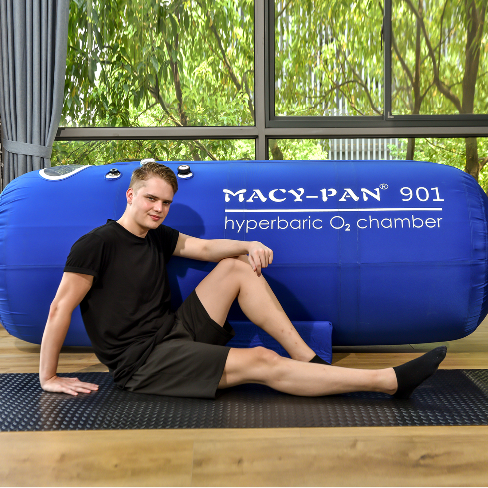 Macy-Pan ST901 Large Soft Lying Hyperbaric Chamber – man sitting beside the chamber