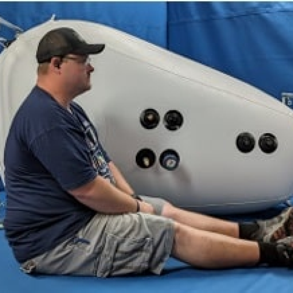 Newtowne C4 Portable Shoe Hyperbaric Chamber – person sitting beside the chamber for scale