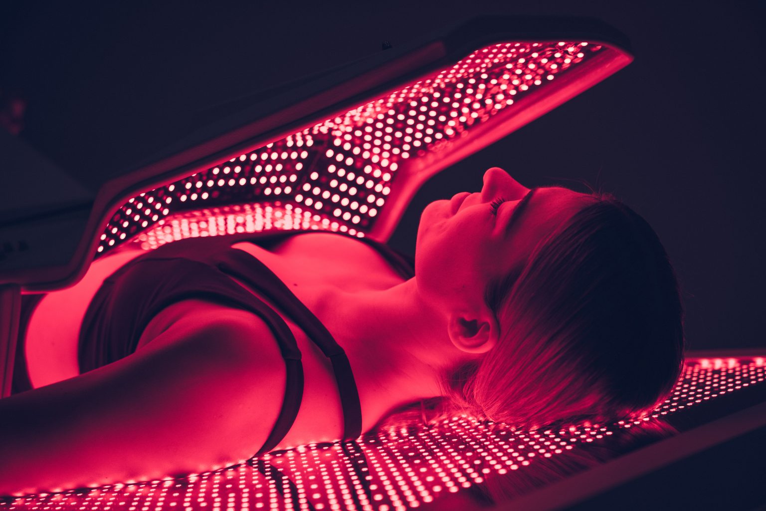 Close-up of woman receiving red light therapy inside OvationULT full-body LED bed.