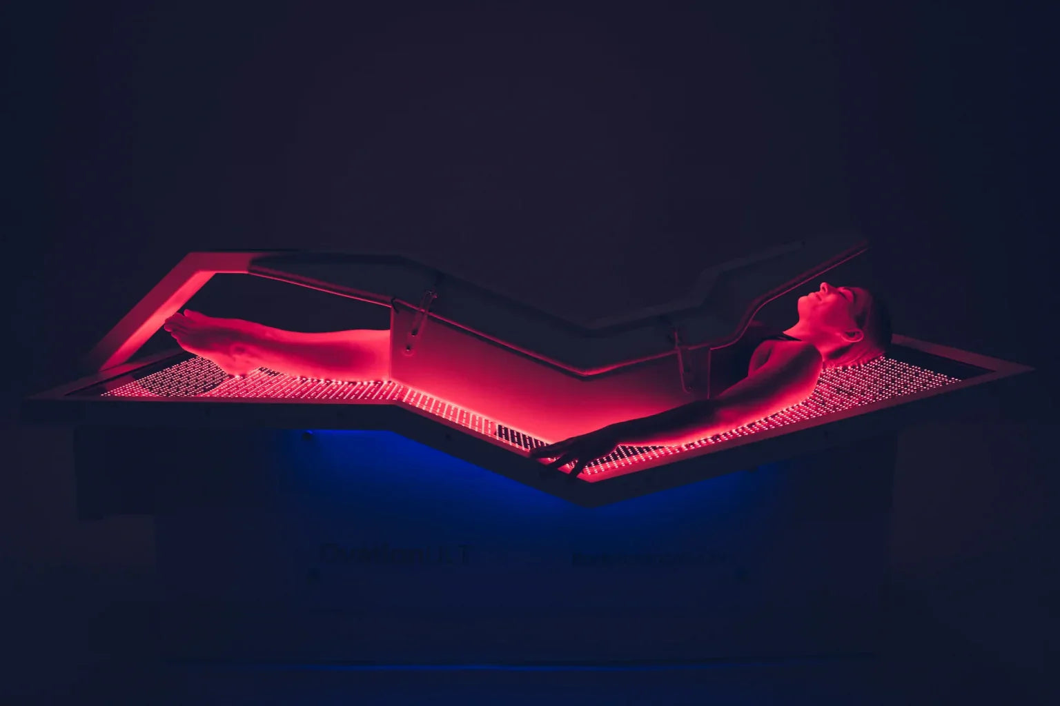 Full-body view of woman inside OvationULT red light therapy bed during active treatment session.