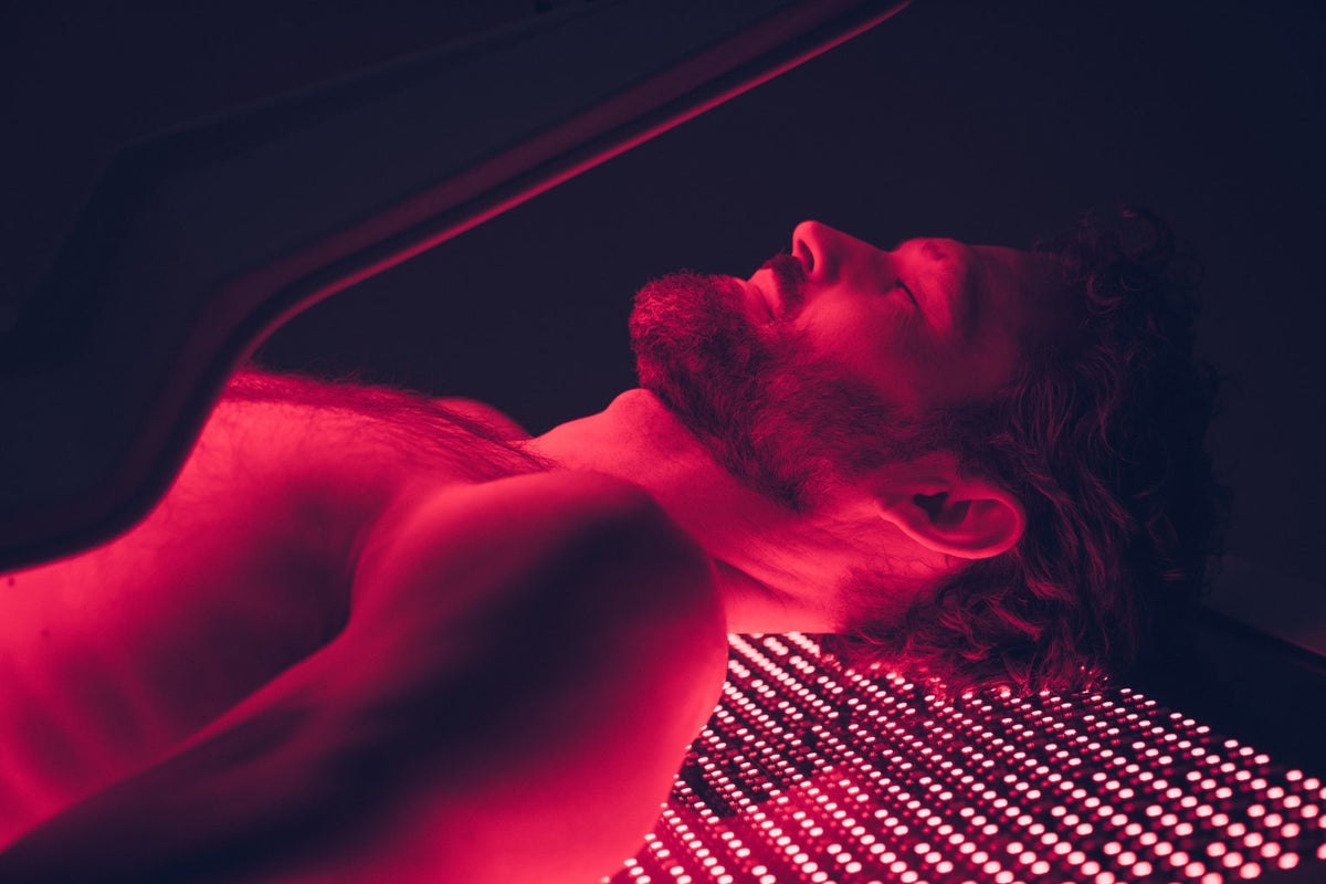Close-up of man receiving full-body red light therapy on OvationULT bed during active session.