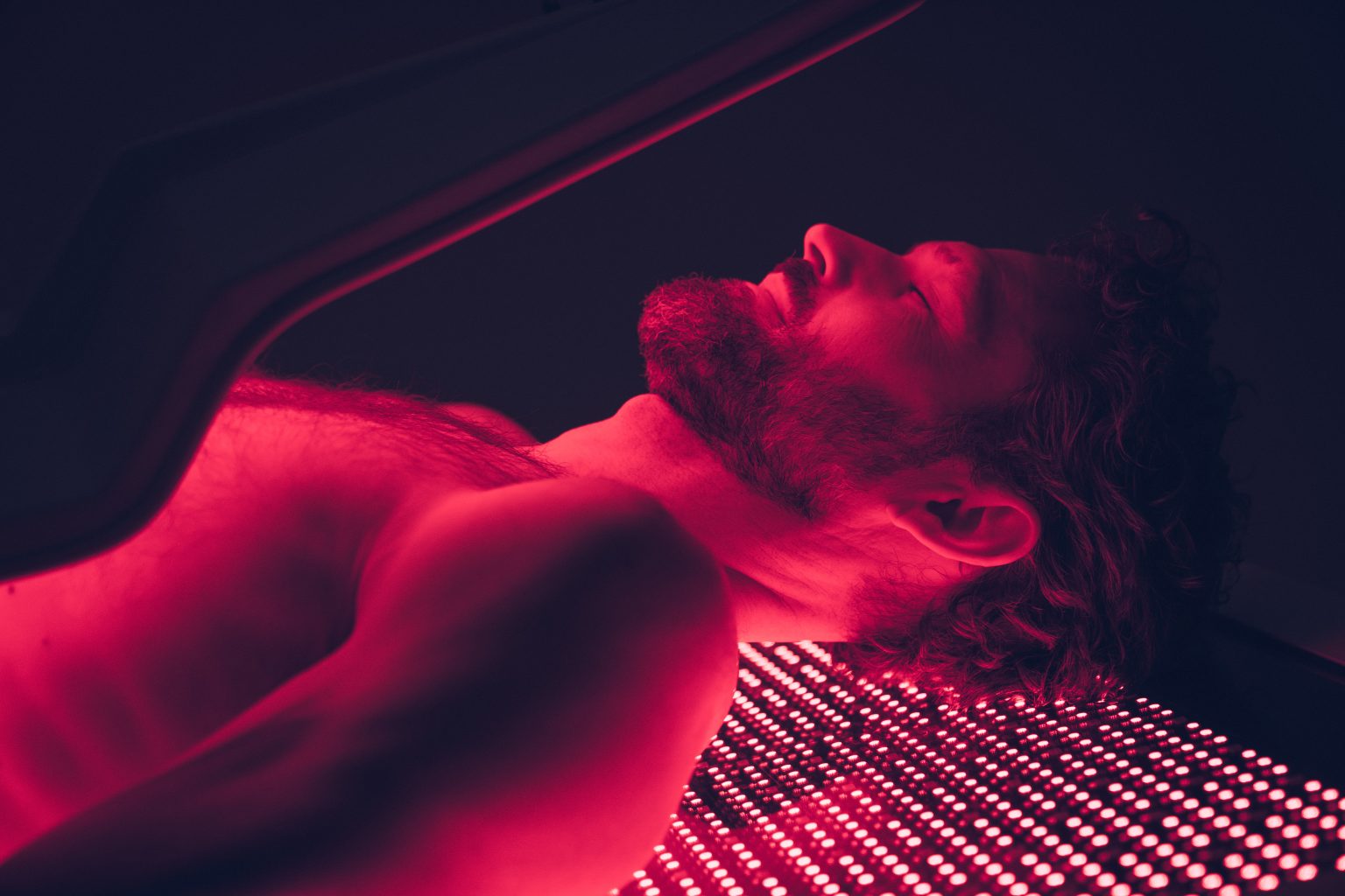 Close-up of man receiving full-body red light therapy on OvationULT bed during active session.