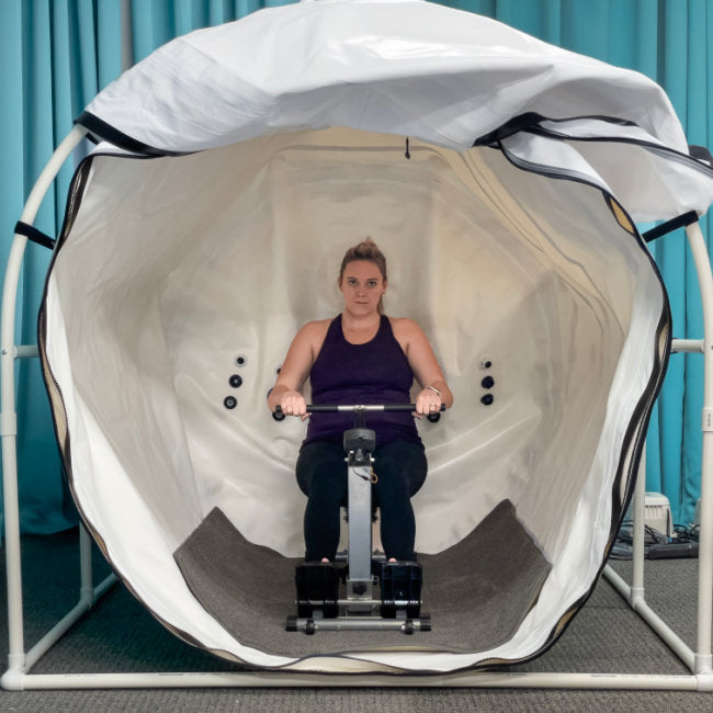 Summit to Sea Grand Dive Pro Plus 60" Hyperbaric Chamber – woman exercising on a rowing machine inside