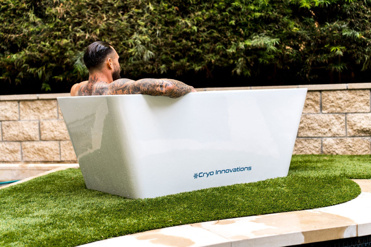 Cryo Innovations XR Cryo Plunge white acrylic tub on a lawn beside a pool, rear view